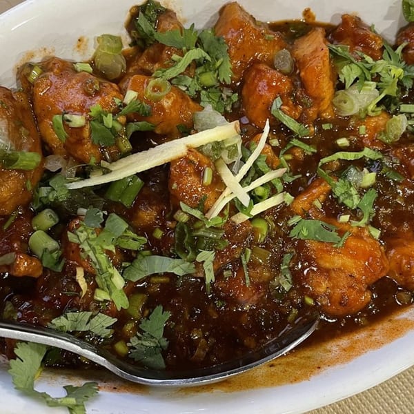 Clay Pit's Chili Chicken, a popular Indian dish, garnished with fresh cilantro and ginger.