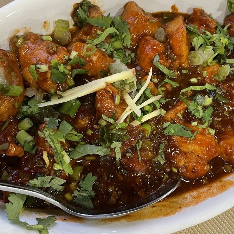 Clay Pit's Chili Chicken, a popular Indian dish, garnished with fresh cilantro and ginger.